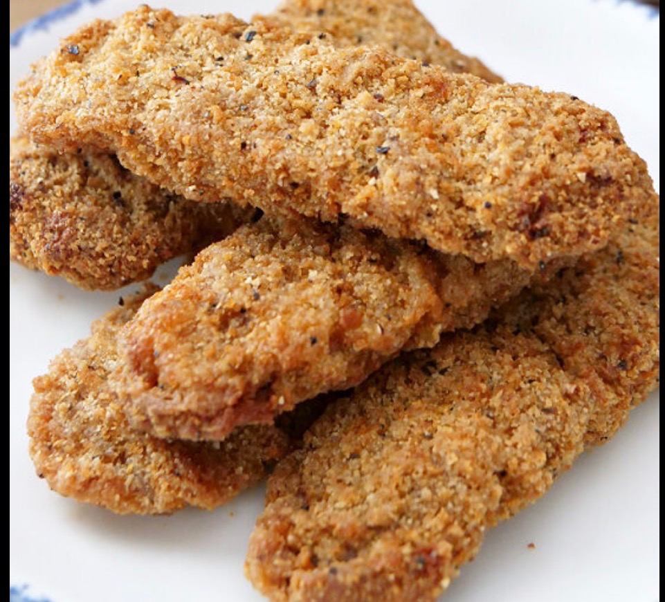 Breaded chicken fingers stacked on a plate